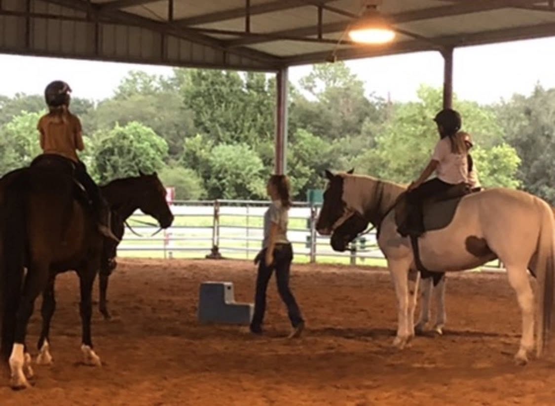 Rider receiving horseback riding instruction in the covered arena at Circle Lake Ranch in Katy, Texas